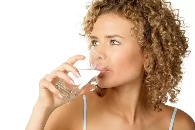 The girl follows a diet for lazy people, drinking a glass of water before eating